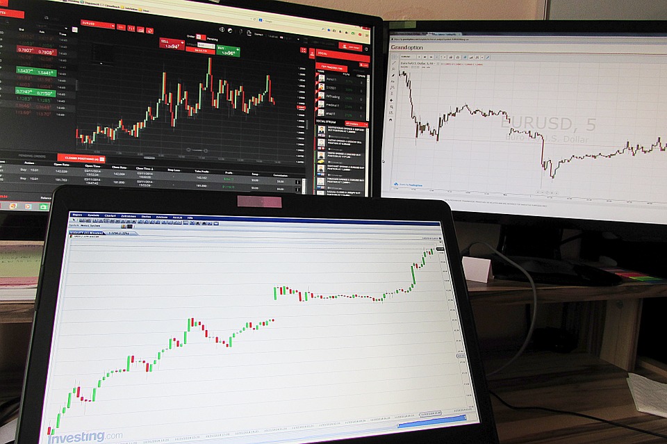 Monitors with charts, representing technical vs fundamental analysis topic.